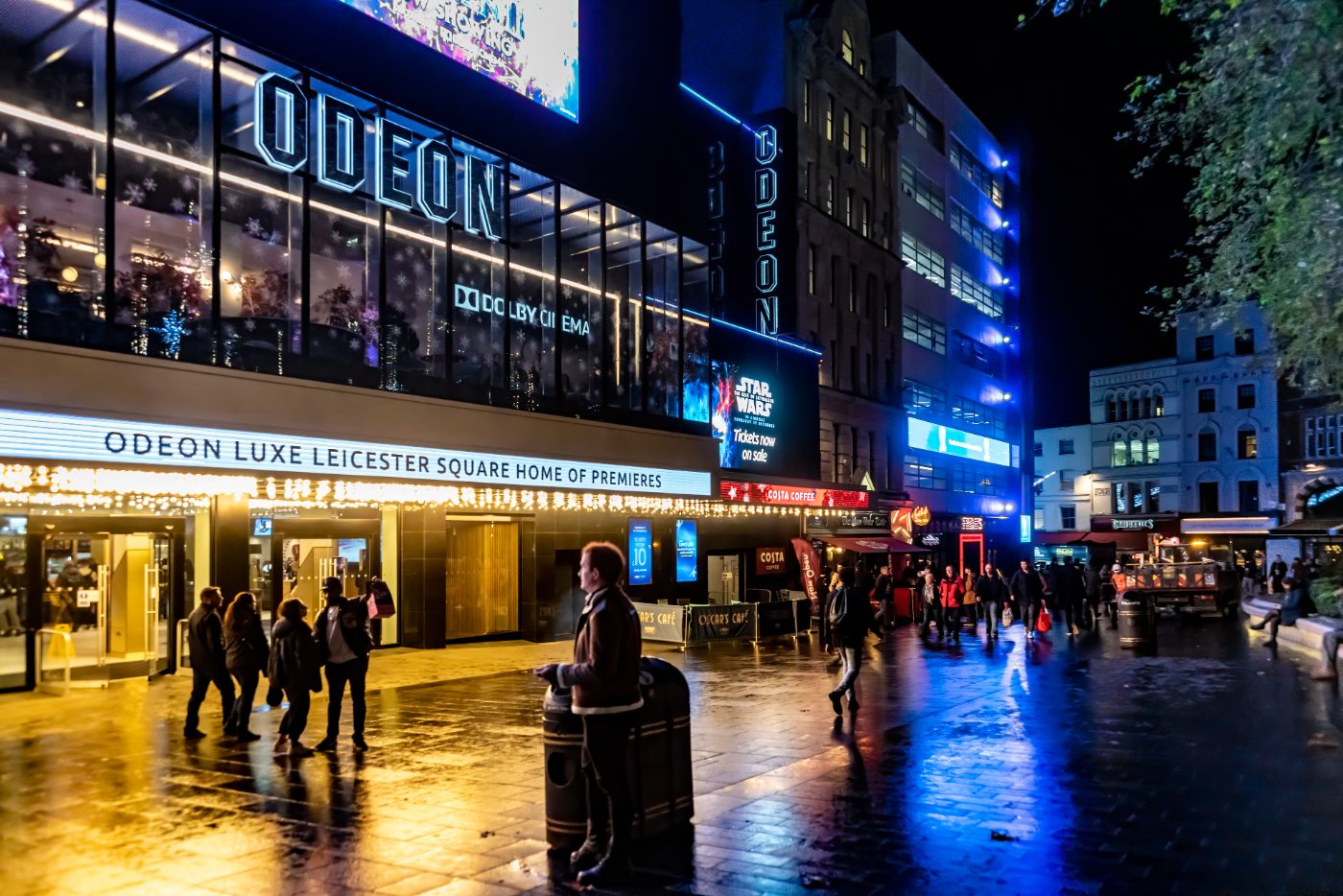 Leicester Square Odeon i London, England, sett om natten ved juletider med turister og handlende som passerer kinoen og lysreklamene.