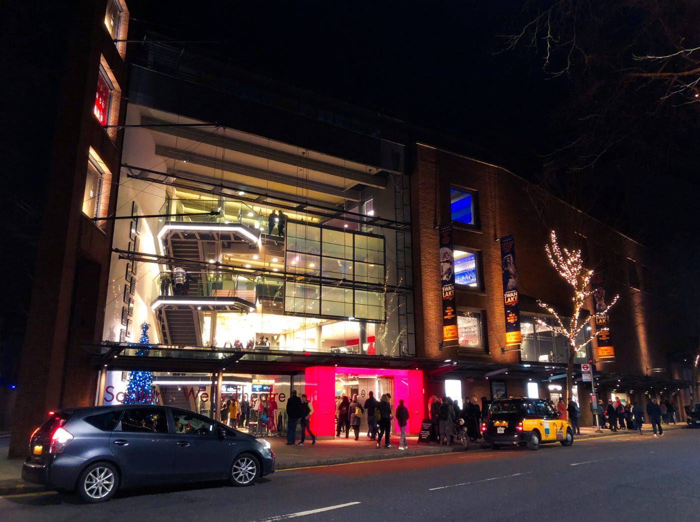 ChatGPT sa: Folk som forlater Sadler’s Wells Theatre etter en kveldsforestilling av Matthew Bournes Swan Lake i juletiden. Teatret er kjent for ballett- og moderne danseproduksjoner, og dagens bygning, åpnet i 1998, er den sjette på stedet siden 1683.