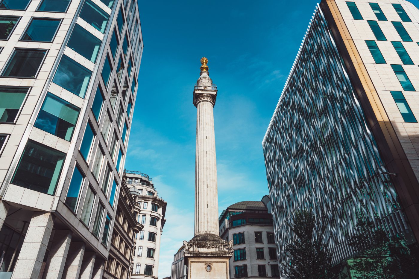 Monumentet over bybrannen i London reiser seg mellom moderne bygninger som et historisk landemerke i samtiden.