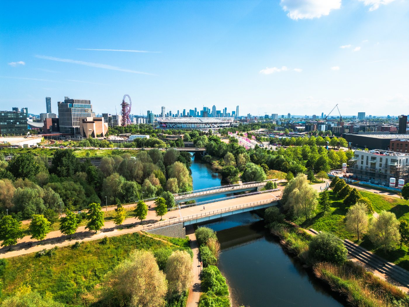 Flyfoto over Stratford i Øst-London med Stratford Wetlands ved River Lea i forgrunnen, Queen Elizabeth Olympic Park og London Stadium i midten, og skyskraperne på Isle of Dogs og Canary Wharf på horisonten.
